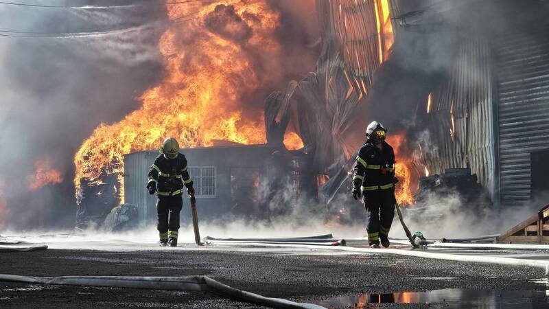 桃园市芦竹区龙安街二段1340巷内一家电缆回收场清晨发生火灾，现场火势猛烈，消防人员冒著烈焰灌救。（记者余瑞仁翻摄）
