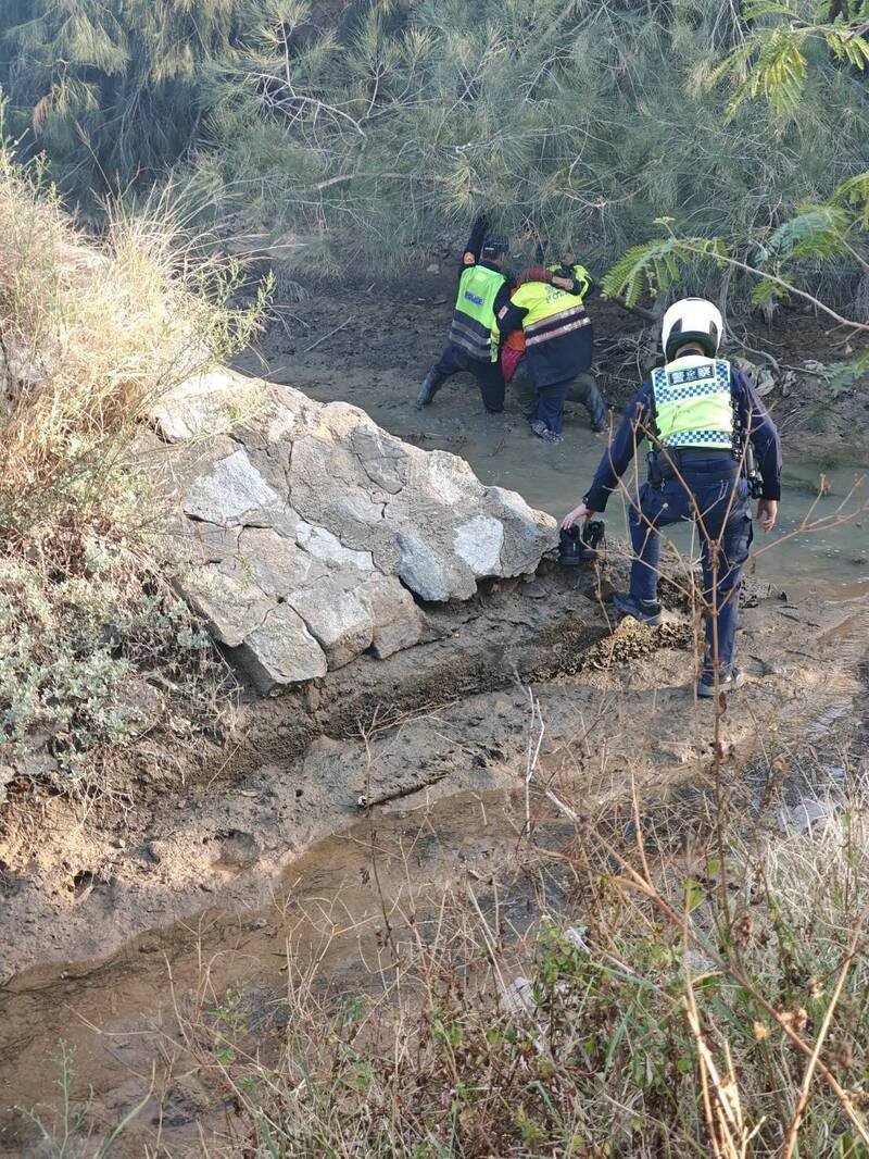 金门一名妇人失踪，县警局金湖分局派员搜索，看见妇人陷在出海口排水沟立刻涉水抢救。（金湖分局提供）