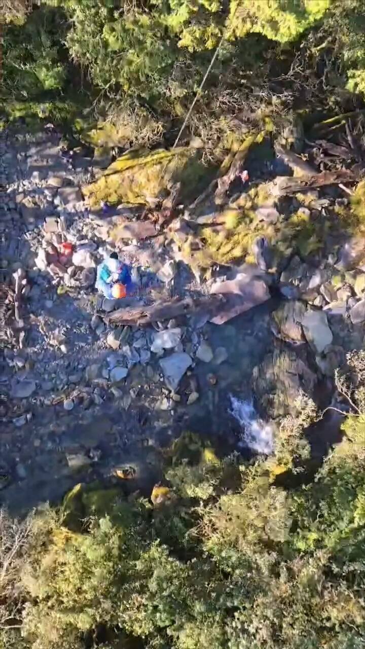 空勤总队花莲出动直升机，今天到太平谷营地附近溪涧救援伤患，将2伤者吊挂上机。（空勤总队提供）