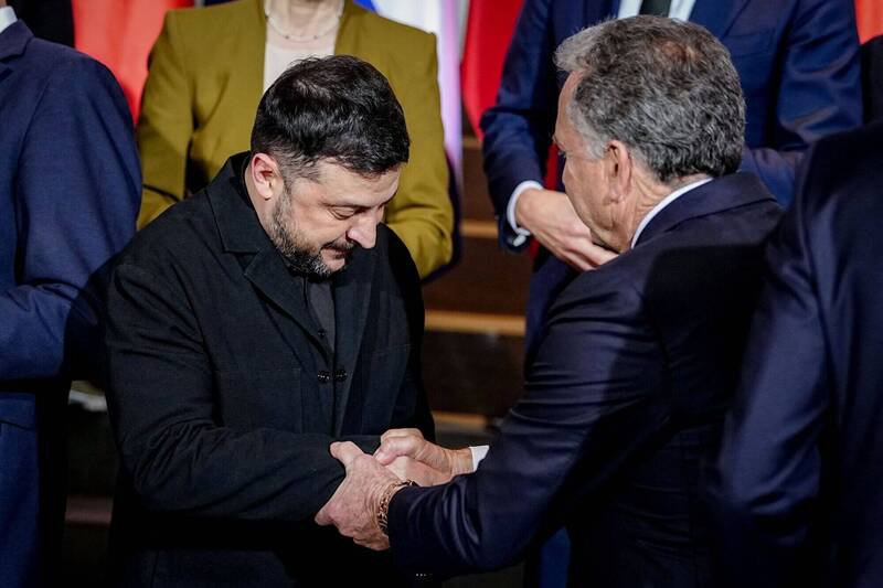 15日的柏林会议中，美国提出愿向乌克兰提供类北约安全保障。图为乌总统泽伦斯基（左）与美国特使魏科夫（右）握手致意。（路透）