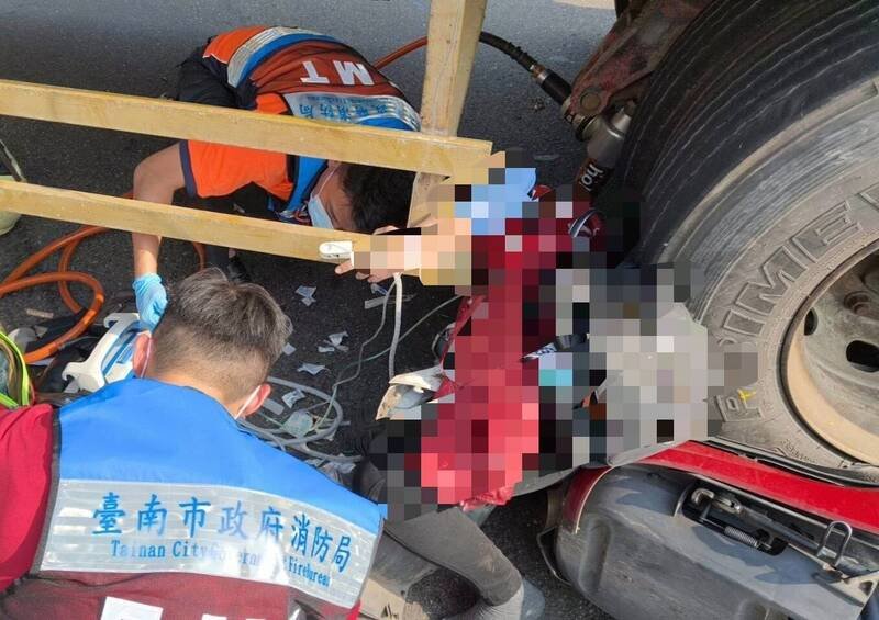 机车与拖板车擦撞后，女骑士卡在轮下，消防队全力抢救。（民众提供）