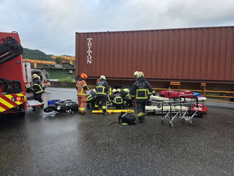 货运曳引车与机车发生碰撞，机车骑士受困车底；新北市消防队员将他救出已无生命迹象，转送基隆急救。（记者林嘉东翻摄）