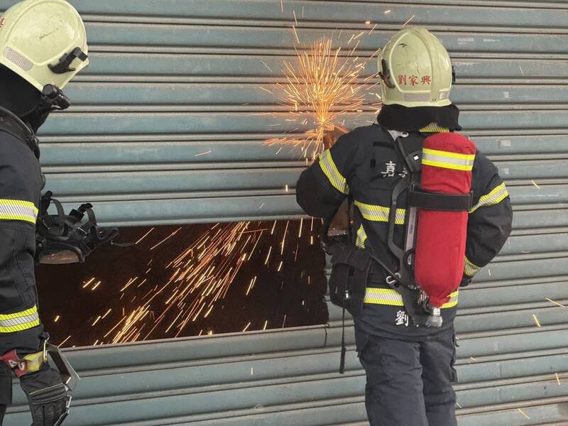 消防员破坏铁卷门进行灭火。（民众提供）