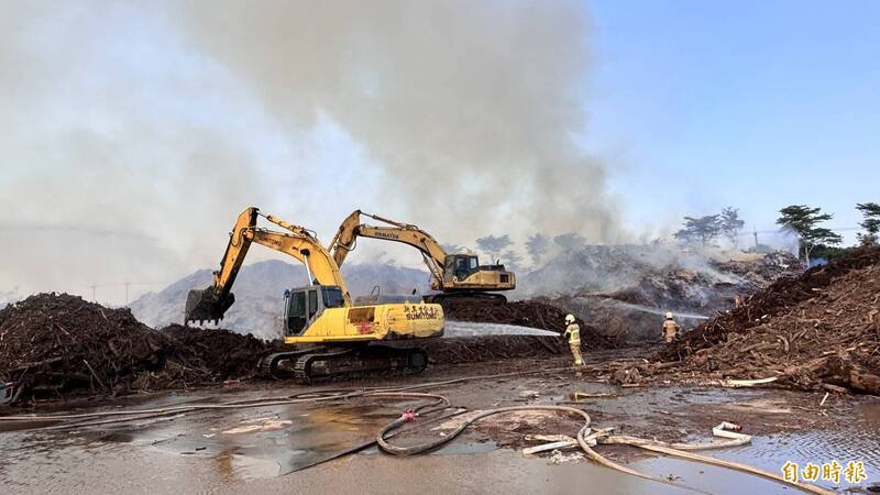 怪手开挖废木堆浇水。（记者杨金城摄）