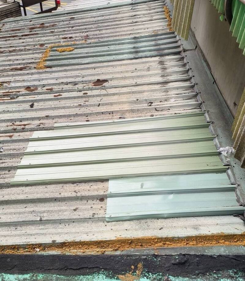 新北市板桥一处社区保全员竟跑到顶楼往楼下丢掷灭火器，造成隔壁社区铁皮屋顶毁损，保全公司得知紧急道歉、协助紧急修复（见图）。（记者吴仁捷翻摄）