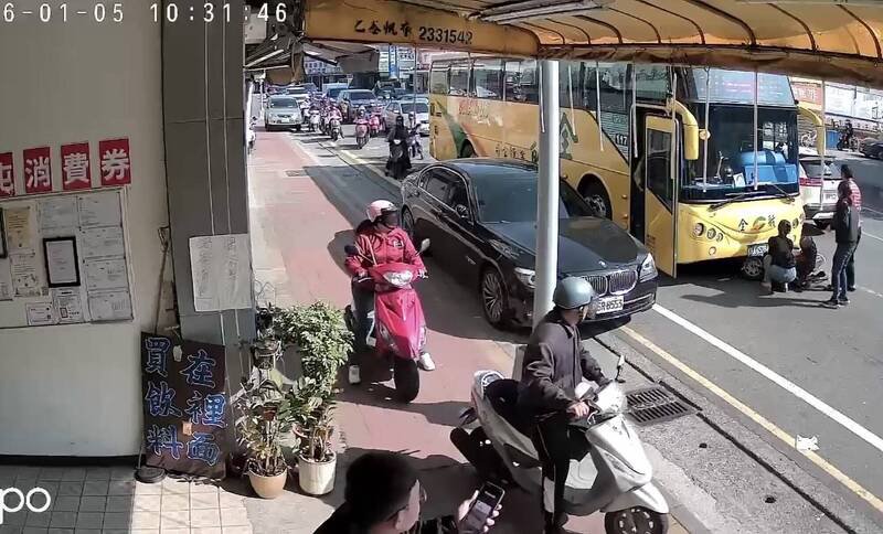 阿嬷骑士和机车卡在直行公车底下，民众想帮忙拉出，行人则赶紧打119。（民众提供）