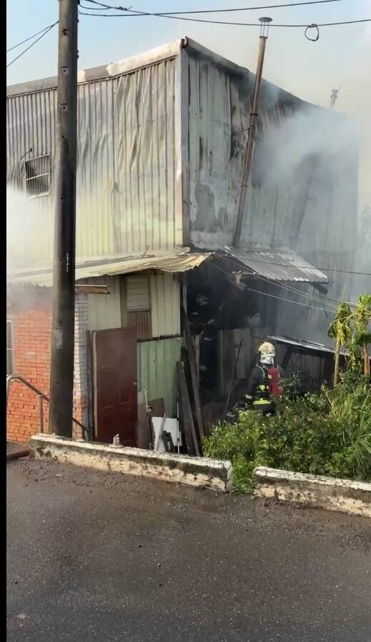 新北市八里一处老宅今天下午窜出火势，消防到场在前阳台救下一人送医，起火原因仍待调查厘清。（记者吴仁捷翻摄）